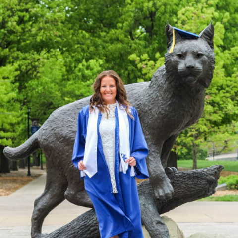 Grace Jenkins in front of Bowman statue in cap and gown, May 2023