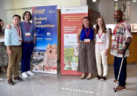 Group photo of Enil, Chris, Savannah, Scarlett, and Teshager standing with banners at the Student Case Study Competition at IFAMA June 2024